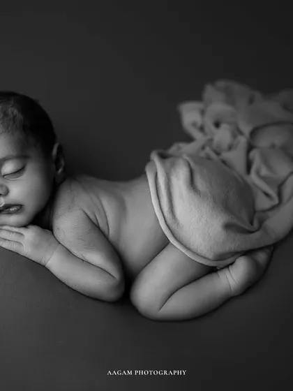 A "cute lil peanut" indeed. This classic newborn pose, captured in black and white, highlights the baby's delicate features and peaceful sleep.