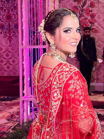 A candid shot of the bride looking back with a joyful smile. Her hair is styled in a beautiful bun with fresh flowers, adding a touch of romance to her look.