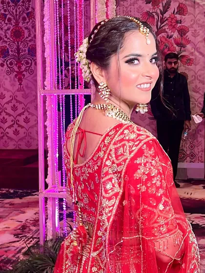 A candid shot of the bride looking back with a joyful smile. Her hair is styled in a beautiful bun with fresh flowers, adding a touch of romance to her look.