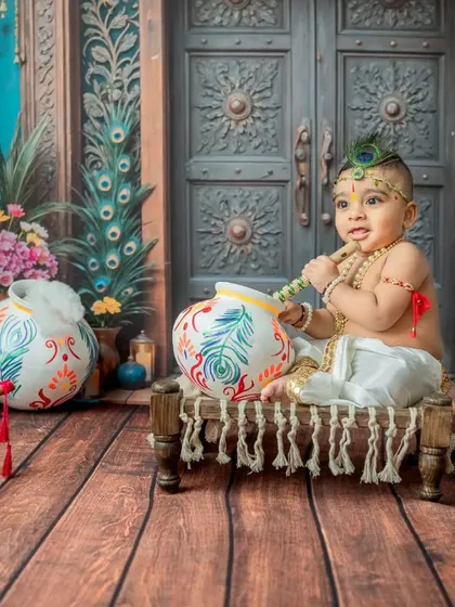 A happy baby Krishna sitting with his pot, clapping his hands with joy.