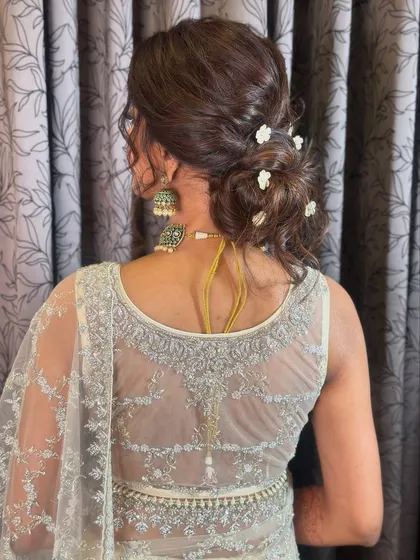 A soft and messy bun with a few delicate white flowers. This is a romantic and modern updo, perfect for a bridesmaid or wedding guest.