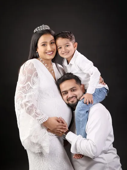 A beautiful family portrait with the older brother getting a piggyback ride from dad, all while hugging mom and her baby bump.