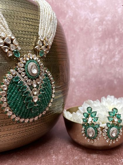 A statement of elegance. This set features a grand pendant with intricate green beadwork and polki, paired with matching earrings, symbolizing tradition, love, and celebration.