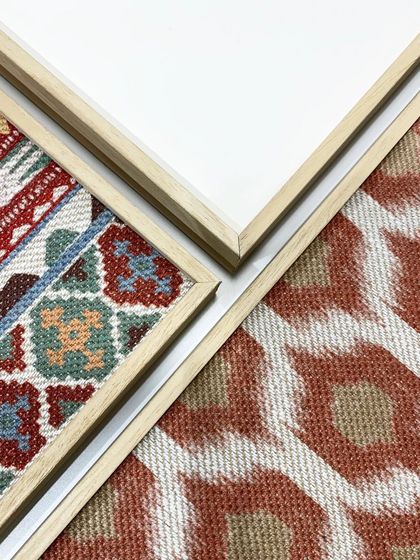 A detail shot showing the corners of different framed textiles. You can see how the clean mitered corners of the frames provide a sharp, professional finish to the soft, textured rugs within.