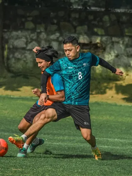 Intense competition as two players challenge for the ball, showcasing the physical and competitive nature of our corporate football events.