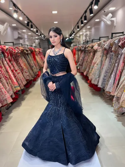 This shot captures the full grandeur of the navy blue fish-cut lehenga against the backdrop of our store. You can see the wide variety of options we have available.