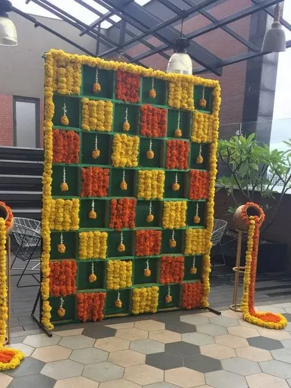 A creative checkerboard selfie wall made entirely of yellow and orange marigolds, perfect for a Haldi or Mehndi event.