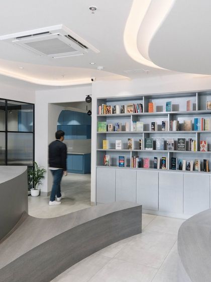 A prominent feature at the entrance is this curved seating element integrated with a large bookshelf. It serves as a library, a waiting area, and an architectural statement that is visible from the street.