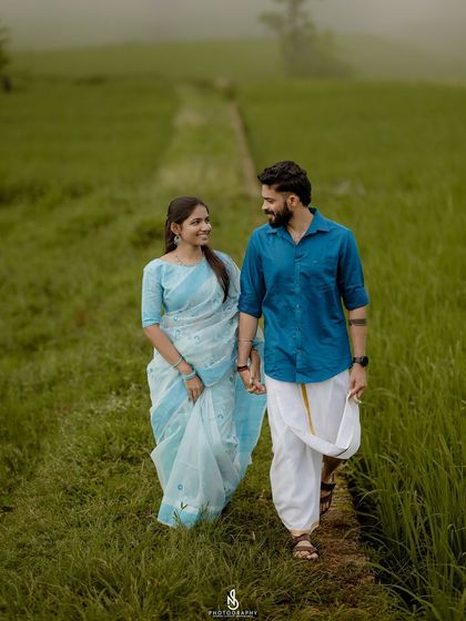 Holding hands and sharing a look as they walk along a narrow path in the field. This image tells a story of their journey together.