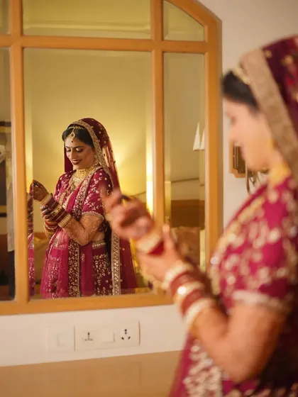 A bride getting ready, looking at her reflection as she puts on her bangles. A classic getting-ready shot.