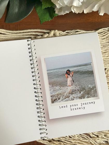 Inside the personalized planner and photo album booklet. Each page has space for a polaroid-style photo with a custom caption, like 'Lead your journey bravely'.