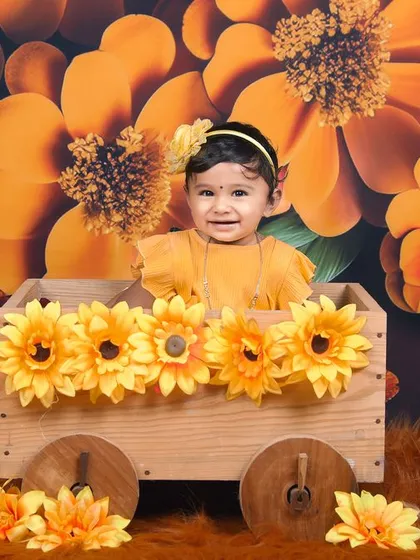A bright and sunny sunflower theme. This little girl is sitting in a wooden wagon adorned with sunflowers, against a vibrant floral backdrop.