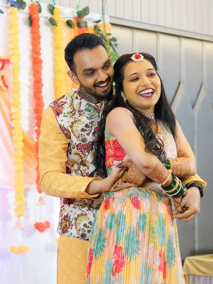 A candid moment of pure joy during the Sangeet. The groom embraces his bride from behind as they share a heartfelt laugh.