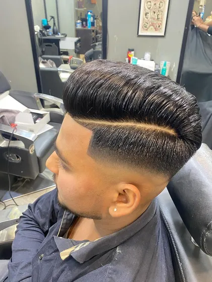 A high-volume pompadour with a hard part and a mid-fade. The defined line of the part makes the style extra sharp.