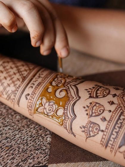A macro shot showing the application of henna paste. You can see the texture of my natural paste and the process of filling in a floral design.