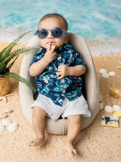 A secret from the seashore. This playful pose with his sunglasses on shows off the fun and creative possibilities of a themed baby shoot.