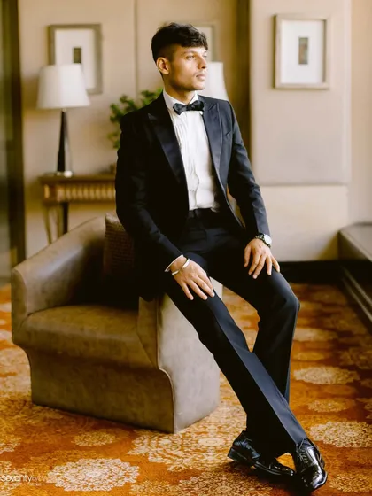 A dapper solo portrait of the groom. His sharp tuxedo and confident pose create a timeless, handsome image worthy of a magazine cover.
