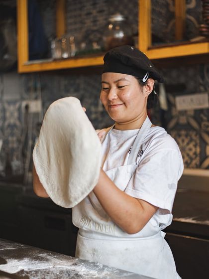Our chefs are artisans. Here, one of our team members expertly stretches the sourdough base, a crucial first step in creating the perfect Neapolitan pizza.