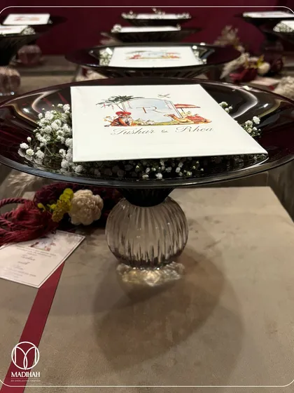 A side view of the Crimson Crystal Bowl on its pedestal, showcasing its fluted crystal base and deep red hue. These are arranged for a wedding event, creating a visually stunning display of favors.