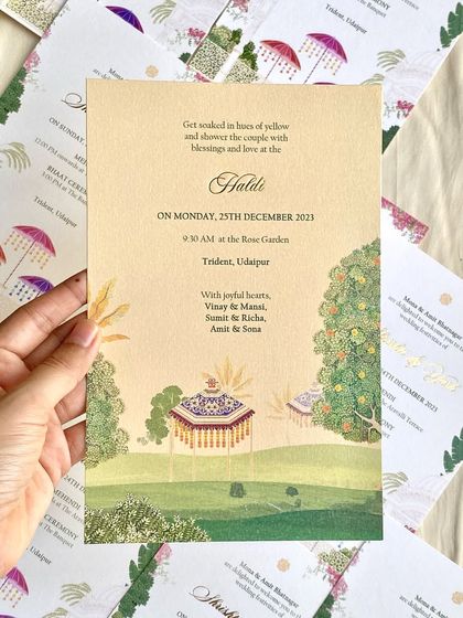 A Haldi invitation for a simple and elegant Udaipur wedding. The design features a gentle watercolor illustration of the garden venue with traditional decorative umbrellas, setting a joyful and serene mood.