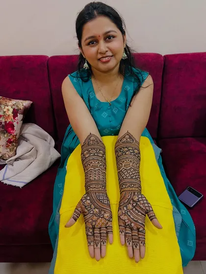 A happy client showing her full bridal mehndi. Her satisfaction is our top priority.