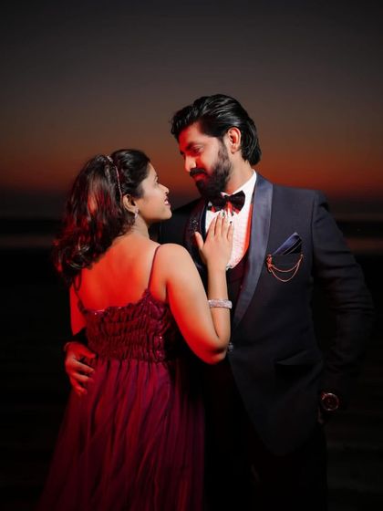 A close-up of the couple from the beach photoshoot, capturing an intimate moment. The detail of the red gown's bodice is visible here.
