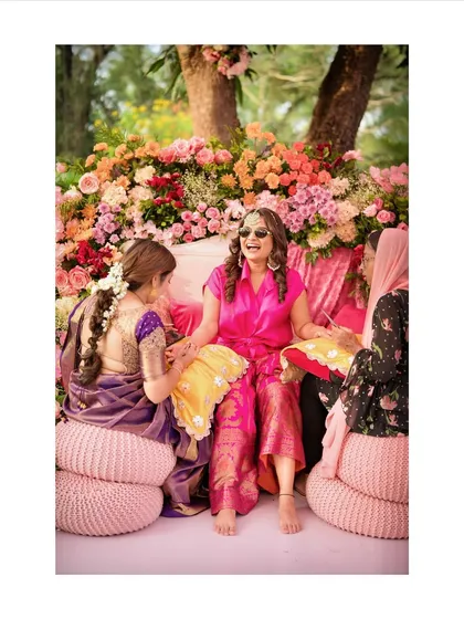 A bride enjoying her Mehendi ceremony, surrounded by a cascade of colorful flowers. The seating is designed to be both comfortable for the bride and a stunning photo opportunity.