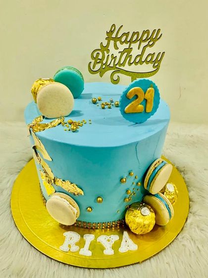 A bright and cheerful blue cake for a 21st birthday, decorated with gold leaf and macarons.