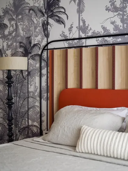Another angle of the master bedroom, showing the interplay between the custom wallpaper, the upholstered headboard, and the handcrafted floor lamp.
