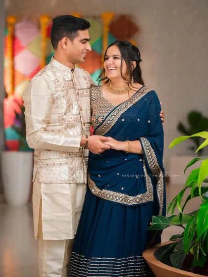 A full-length shot of a beautifully dressed couple, capturing their joyful interaction. This photo highlights their coordinated ethnic wear, perfect for an engagement or Roka ceremony.