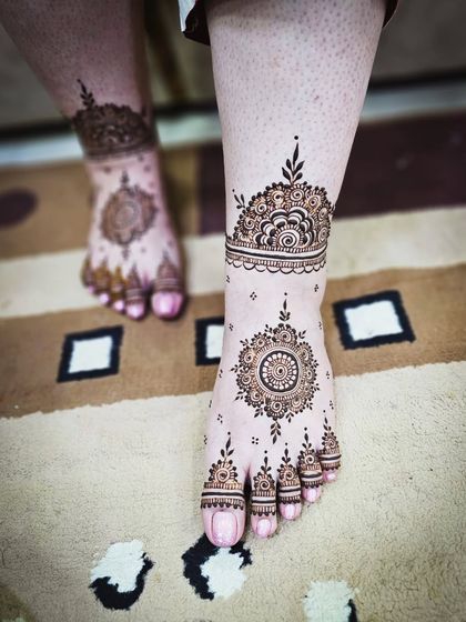 A lovely foot design that complements the bride's hand henna, featuring a central mandala and ankle cuff.
