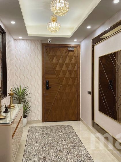 The view towards the entrance door of the foyer. The 3D wallpaper, designer door with a smart lock, and elegant chandeliers all work together to create a warm and luxurious welcome.