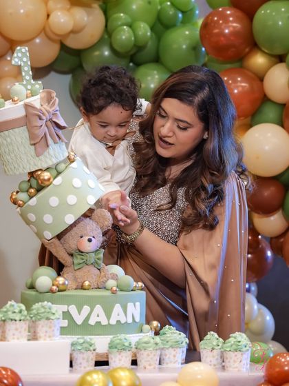 Showing my son the details on his first birthday cake. The teddy bear and gift box structure was a challenge, but so worth it.