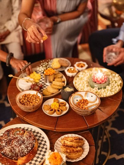 A top-down view of a well-loved grazing table, with hands reaching in to enjoy the variety of snacks. Our spreads are designed to be interactive and delicious.