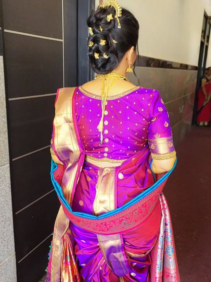 A view of the back of the Nauvari drape and the traditional 'Khopa' hairstyle. The saree is secured neatly at the back, allowing for ease of movement.