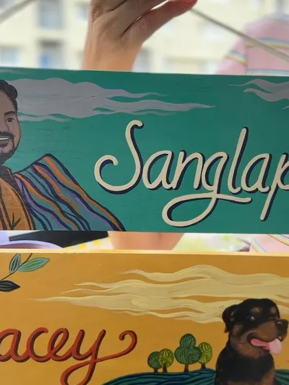 A detailed shot of the three-tier nameplate, focusing on the hand-painted names and portraits of the family members.