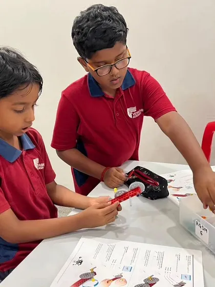 Two students from Vidyashilp Academy work together on a gear mechanism, learning about mechanical principles through hands-on building.