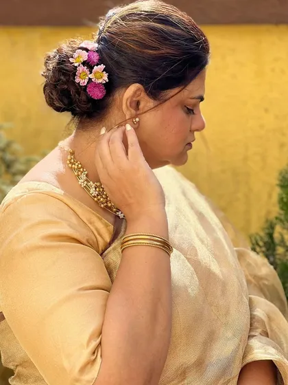 A close-up of the hairstyle, a simple bun decorated with a few fresh flowers for a touch of elegance.