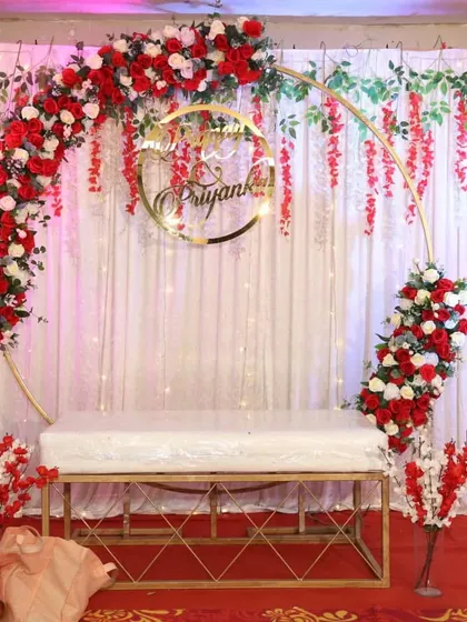 For this sakharpuda, the theme was red and white. We created a semi-arch design with hanging floral strings and a custom golden name hoop for a simple yet beautiful look.