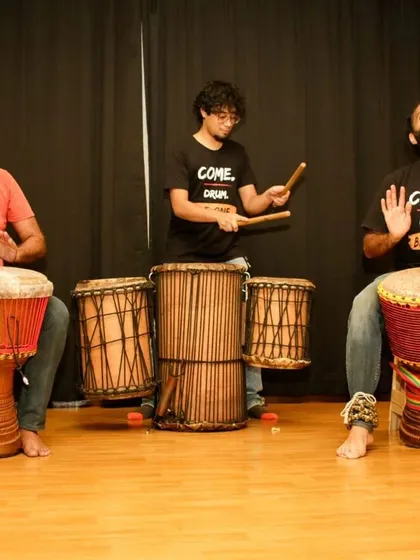 A performance by my djembe students' ensemble. This shows the progression from learning in class to performing on stage, wearing our 'Come. Drum. Be One.' shirts with pride.