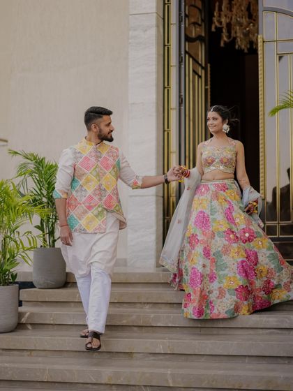 The couple makes a grand entrance at their Haldi ceremony, hand in hand, their colorful outfits perfectly matching the festive theme.