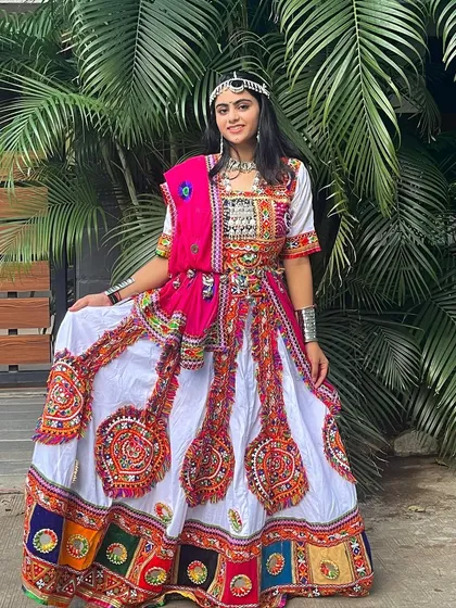 A full-length view of this stunning white lehenga with a colorful border and a bright pink dupatta. It’s a fresh and vibrant choice for Navratri.