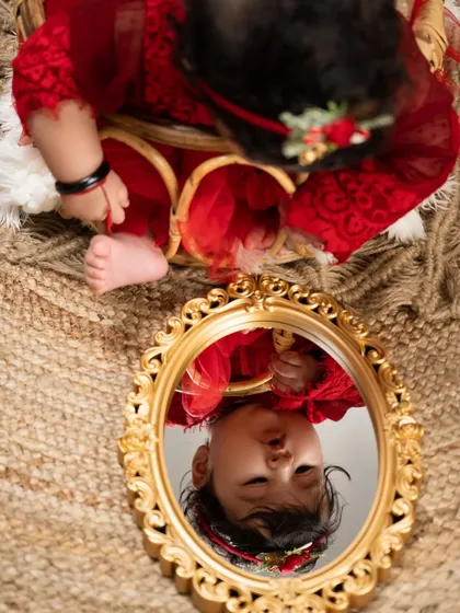 A moment of reflection. This artistic shot captures a baby's fascination with her own image in a vintage-style mirror, a beautiful way to document self-discovery.