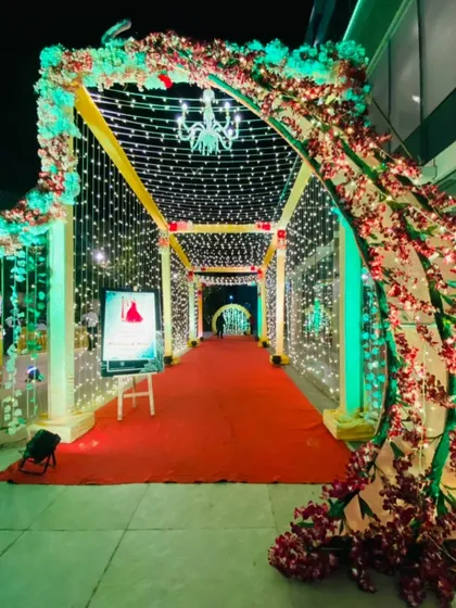 A beautiful entrance walkway framed by artificial cherry blossom trees and a canopy of fairy lights, creating a romantic, spring-like atmosphere.