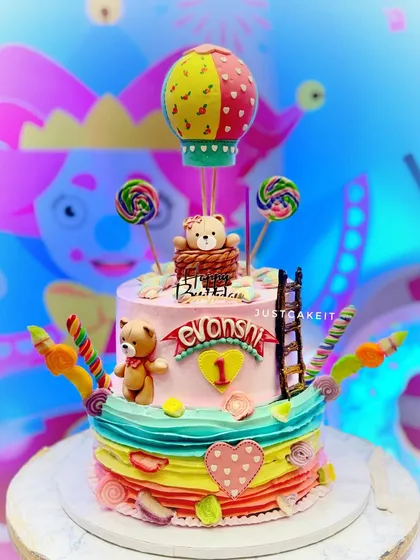 A colorful 5kg Nutella chocolate cake for a first birthday. The design is a fantasy of color, featuring a teddy bear in a hot air balloon and lots of candy accents.