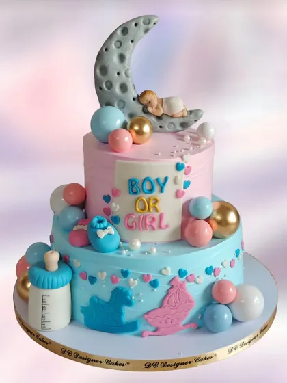 A two-tier "Boy or Girl" baby shower cake with a sleeping baby on the moon. The pink and blue colors are beautifully blended, creating a dreamy and sweet centerpiece.