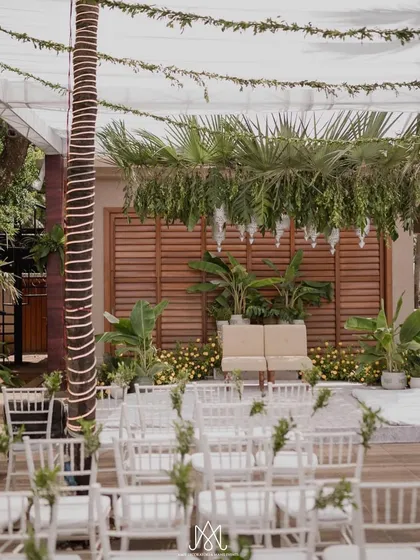 The aisle view of the minimalist wedding setup, showing how simple elements like white chairs and a fabric canopy can create a beautiful and serene ceremony space.