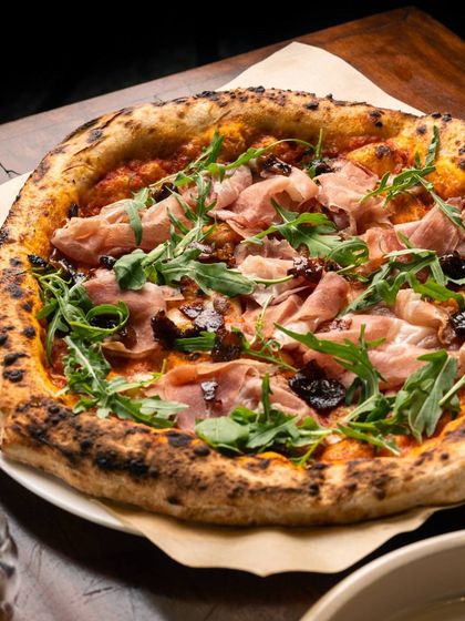 Grab a slice and unwind. This pizza, topped with prosciutto, figs, and arugula, is a sophisticated combination of sweet and savoury, perfect for a relaxed evening.