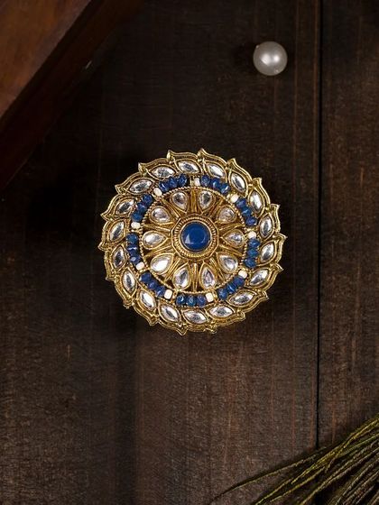 A large, ornate traditional Indian ring with blue stones, styled with peacock feathers. This composition creates a royal and ethnic vibe, perfect for traditional jewellery.