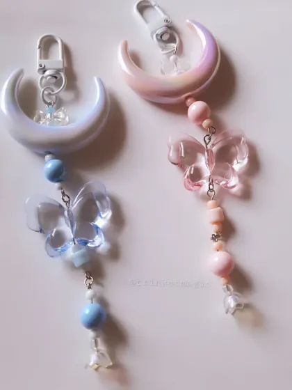 Dreamy and celestial, these bag charms feature large moon pendants and translucent butterfly charms in soft pink and blue hues.